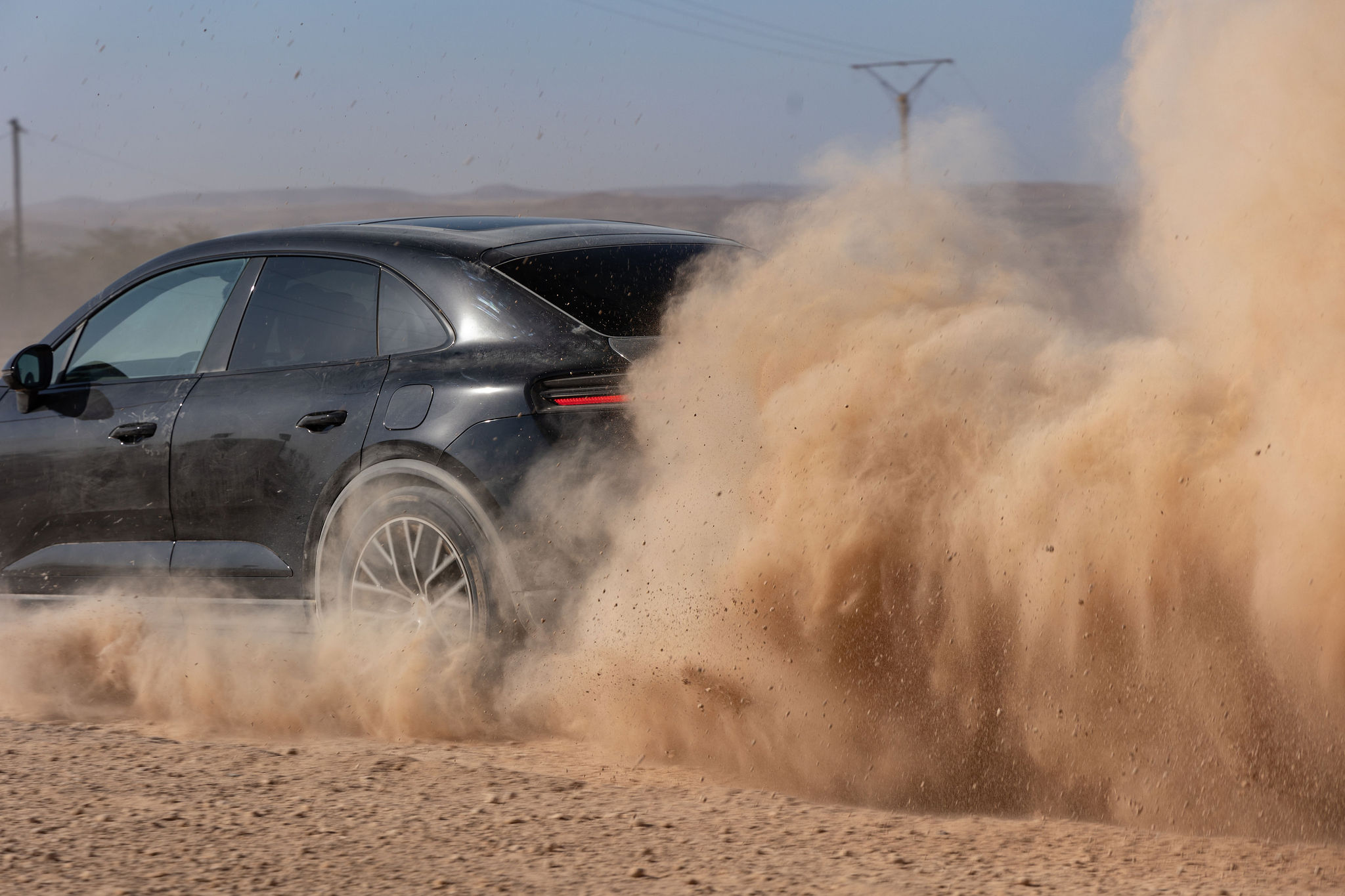 Porsche Macan électrique soulevant un nuage de poussière dans le désert d’Agafay