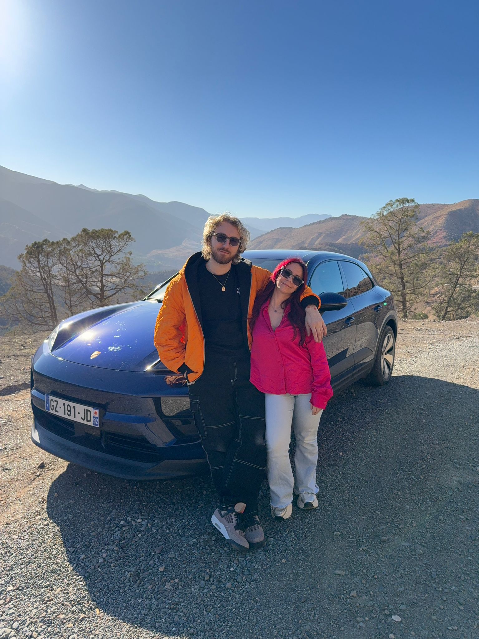 Sora et Adeline Chetail posant devant le Porsche Macan électrique dans le désert d’Agafay