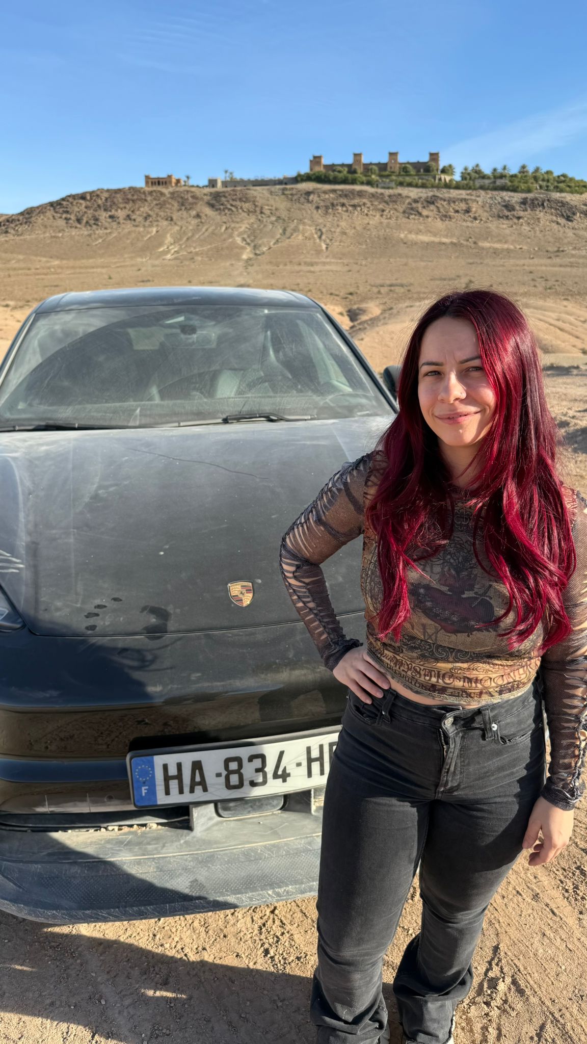 Adeline Chetail posant devant le Porsche Macan électrique dans le désert d’Agafay