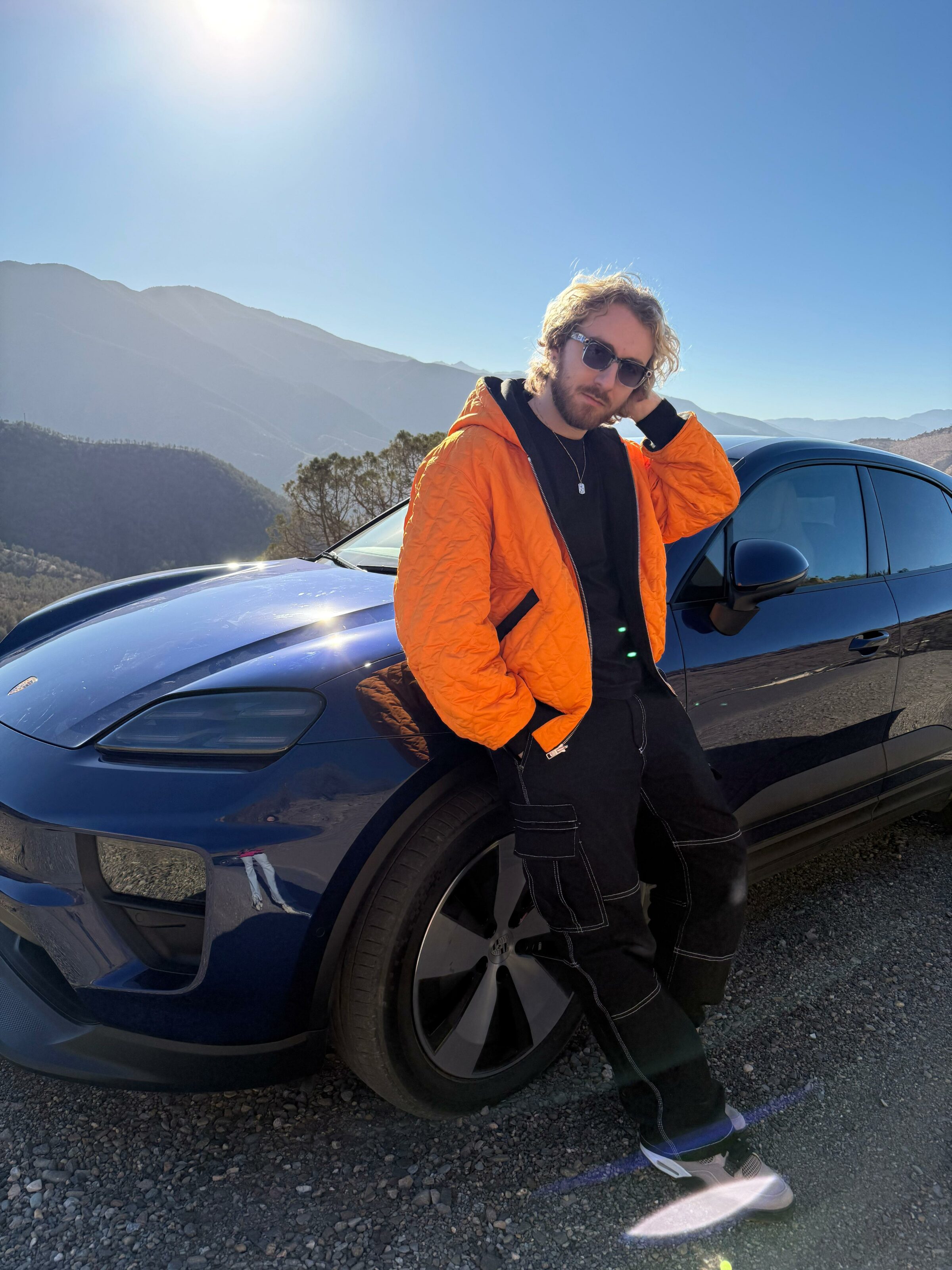 Sora posant devant le Porsche Macan électrique dans le désert d’Agafay